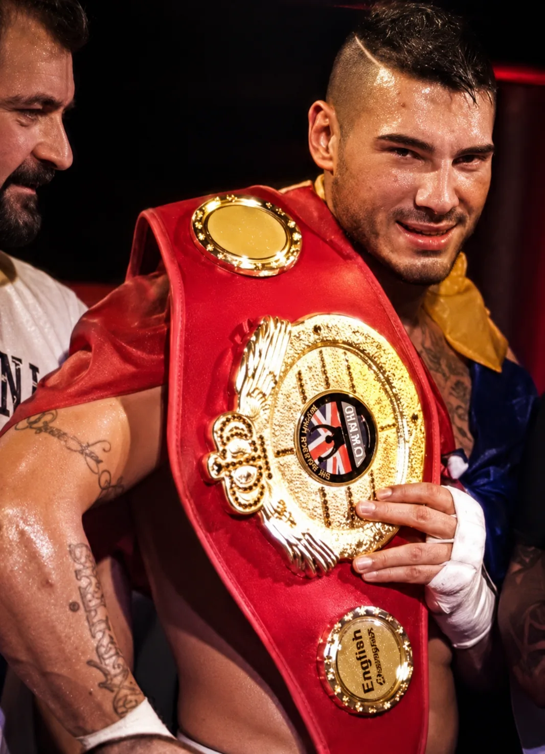 Sportiv în ring, imediat după meci, cu centura de campion pe umăr.