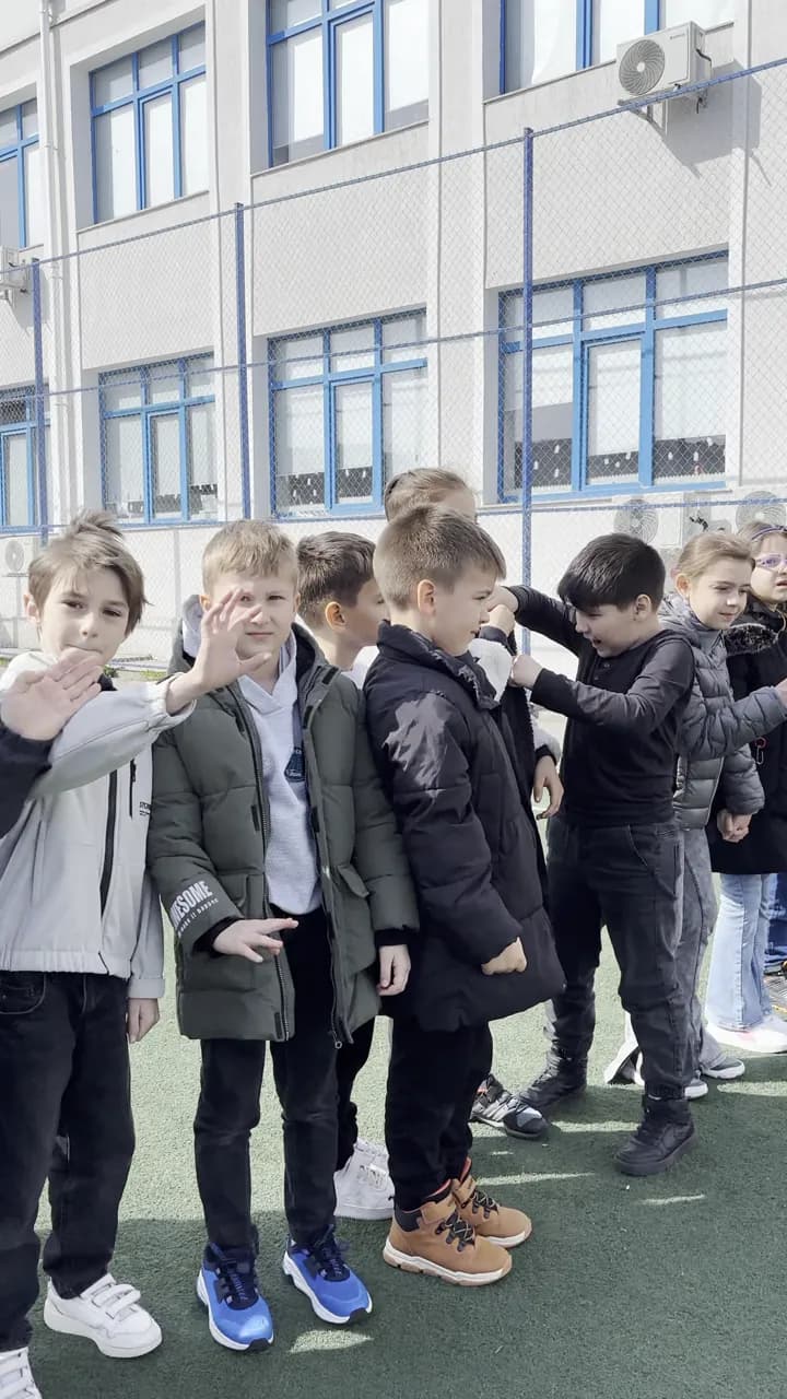 Elevi aliniați pe terenul de sport al unei școli, cu profesorii lângă ei.